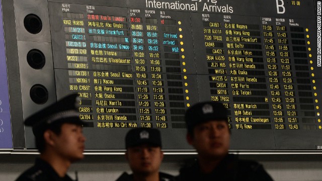 Chinese police at the Beijing airport stand beside the arrival board showing delayed Flight 370 in red on March 8.