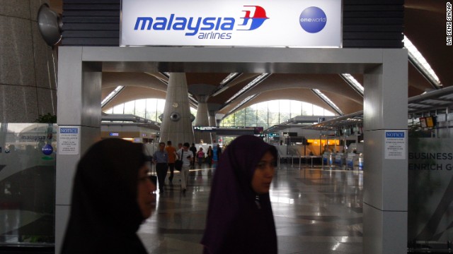 Passengers walk past a Malaysia Airlines sign on March 8 at Kuala Lumpur International Airport.