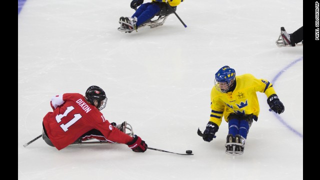 Adam Dixon of Canada, left, and Per Kasperi of Sweden, right, compete in the ice sledge hockey match on March 8. 