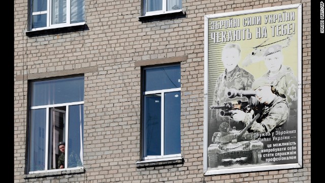 A Ukrainian soldier looks out of the window of a regional military building with a poster reading "Ukraine's armed forces wait for you!" in Donetsk on March 13.