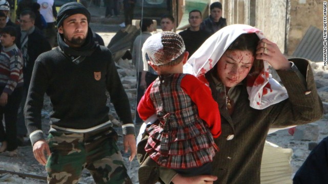 A woman with blood on her face carries a child following a reported airstrike by government forces Saturday, March 15, in Aleppo.