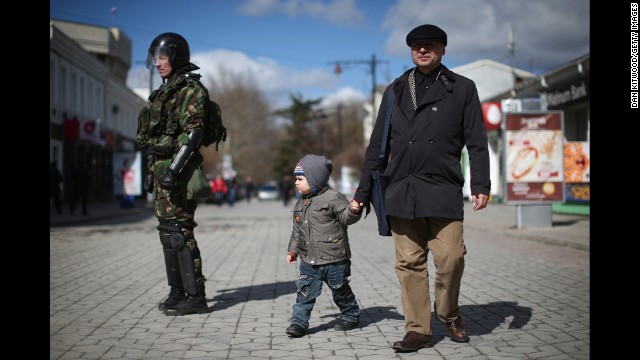 Civilians walk past riot police in Simferopol on March 17.