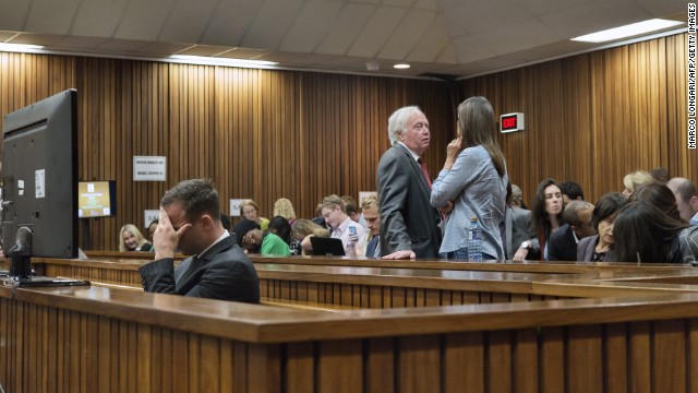 Pistorius holds his head while members of his family talk behind him on Tuesday, March 18.