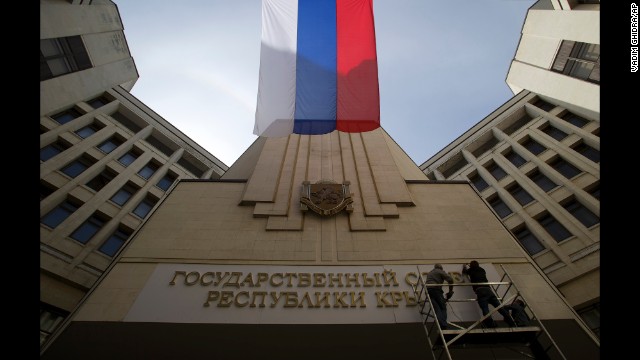 A Russian flag waves as workers install a new sign on a parliament building in Simferopol, Crimea's capital, on March 19.