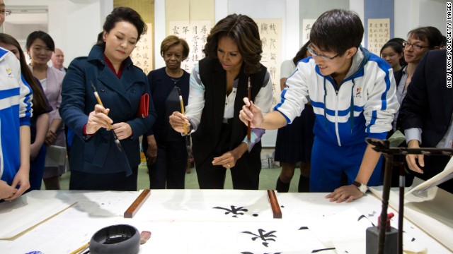 Peng Liyuan, wife of Chinese President Xi Jinping, left, shows first lady Michelle Obama how to hold a writing brush as they visit a Chinese traditional calligraphy class in Beijing on Friday, March 21. The first lady is on <a href='http://www.cnn.com/2014/03/21/politics/gallery/michelle-obama-china/index.html'>an official visit</a> to expand relations between the United States and China. Click through the gallery to see her other international travels through the years.