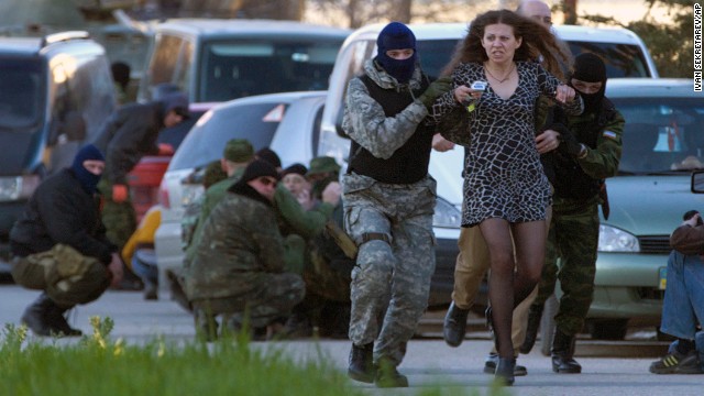 Pro-Russian militia members evacuate a local resident as Russian troops assault the Belbek air base, outside Sevastopol, Crimea, on Saturday, March 22. On Saturday, six Russian special forces armored personnel carriers broke through the gates of the air base, firing warning shots into the air, a spokesman for Ukraine's Ministry of Defense in Crimea told CNN. Russia's military activities in Crimea and its move to annex the region have been condemned by Ukraine's interim government in Kiev, the European Union and the United States. The standoff has sparked an international crisis, reviving concerns of a return to Cold War relations.