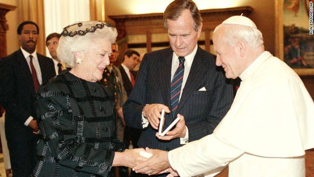 Pope John Paul II presents first lady Barbara Bush with a Vatican Medal as President George H.W. Bush looks at his medal during a ceremony at the Vatican in 1989.