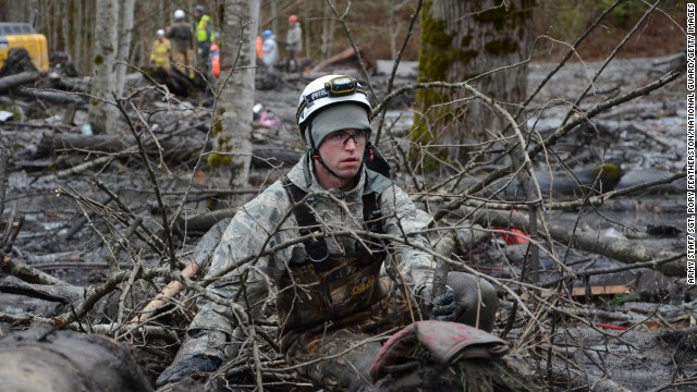 Staff Sgt. Jonathon Hernas of the Air National Guard carefully makes his way across debris and mud while searching for missing people March 29 in Oso.