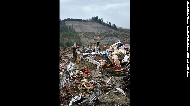 Air National Guard members look out at the hill where the landslide originated while they search through debris March 29 in Oso. 