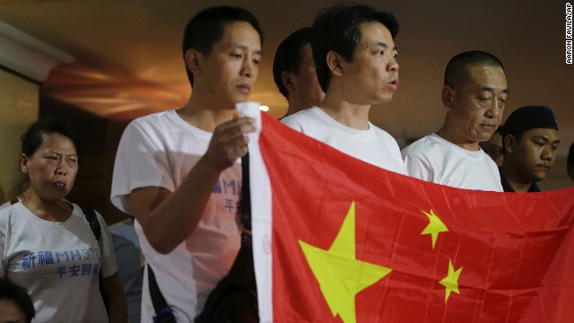 A teary-eyed woman listens from the back as other relatives of Chinese passengers on board the missing Malaysia Airlines Flight 370 speak to reporters Sunday, March 30, in Subang Jaya, Malaysia. Dozens of anguished Chinese relatives demanded that Malaysia provide answers to the fate of those on board.