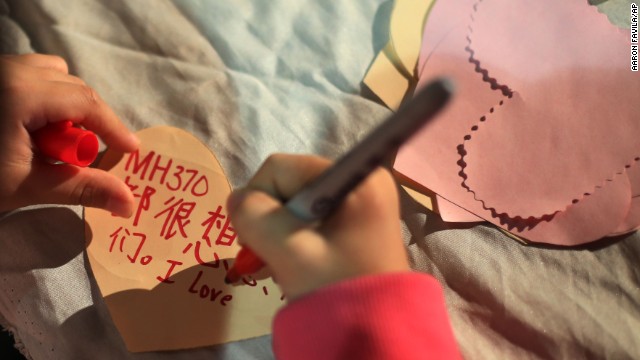 A girl in Kuala Lumpur writes a note during a ceremony for the missing passengers on March 30.