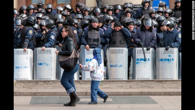 A woman and child walk past a line of police officers during a rally in Kharkiv, Ukraine, on March 30.