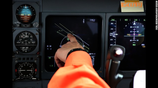 A member of the Japanese coast guard points to a flight position data screen while searching for debris from the missing jet on Tuesday, April 1.