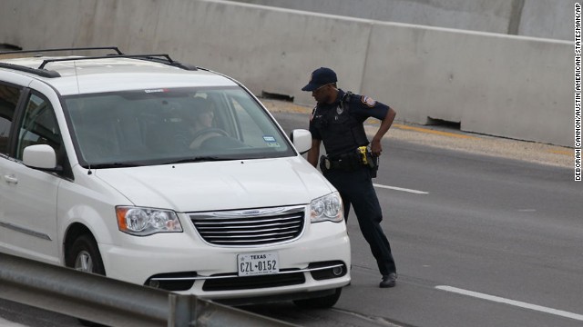 A police officer checks drivers' IDs outside the main gate at Fort Hood.