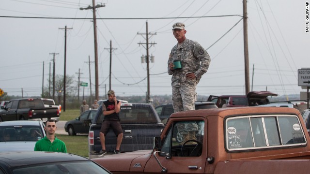 Military personnel and civilians wait outside Fort Hood for updates on the situation.