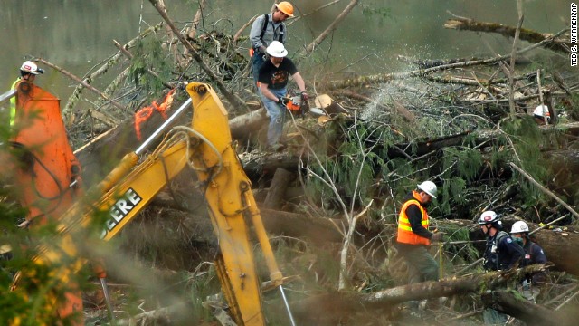 Workers cut a tree next to a possible victim on Sunday, March 30.