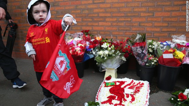 A young fan stands next to floral tributes laid in memory of the victims ahead of the Liverpool-Manchester City game at Anfield.