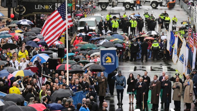 People pause Tuesday, April 15, as the American flag is raised at the finish line of the Boston Marathon, where two homemade bombs went off one year ago. It was the deadliest terrorist attack in the United States since 9/11.