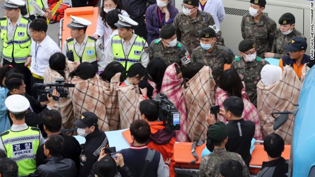Officials escort rescued passengers April 16 in Jindo.