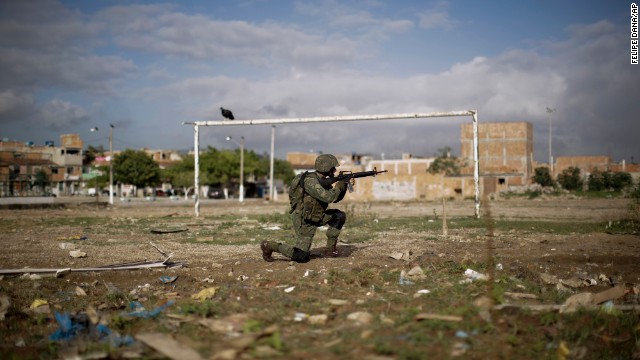 A member of the military patrols a soccer field.