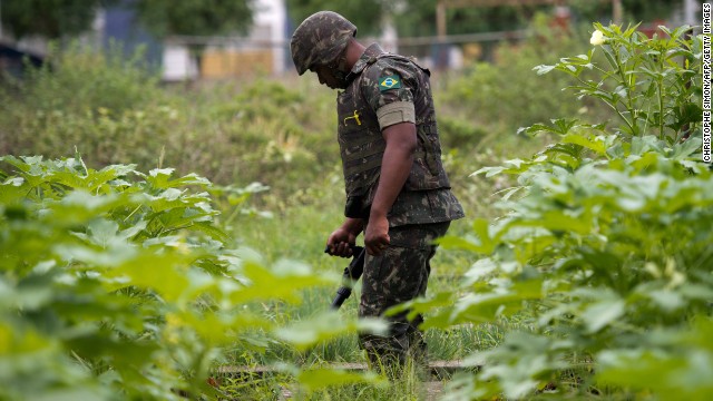 A Brazilian soldier with a metal detector searches for buried weapons in the favela.