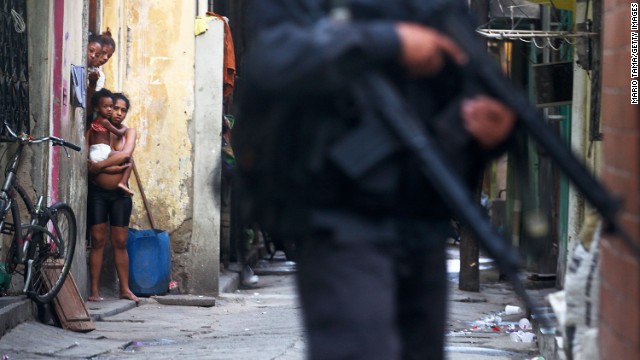 Residents look on as military police officers patrol the Complexo da Mare on March 30.