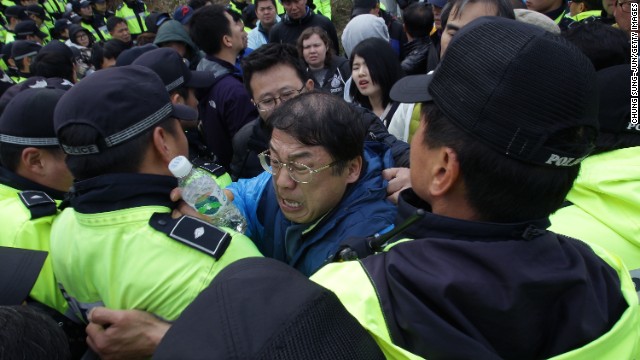 Relatives of passengers missing from the sunken ferry scuffle with police as they try to leave Jindo.