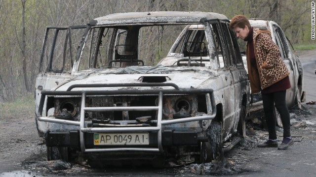 A local resident inspects burnt-out cars after the incident at the roadblock on April 20. 