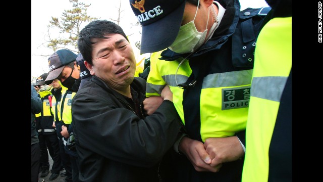 A relative of a missing passenger struggles with a policeman as he tries to march toward the presidential house in Jindo on April 20 to protest the government's rescue operation.