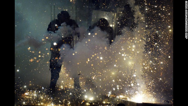 Police officers shield themselves from fireworks thrown by protesters in Caracas on April 20.