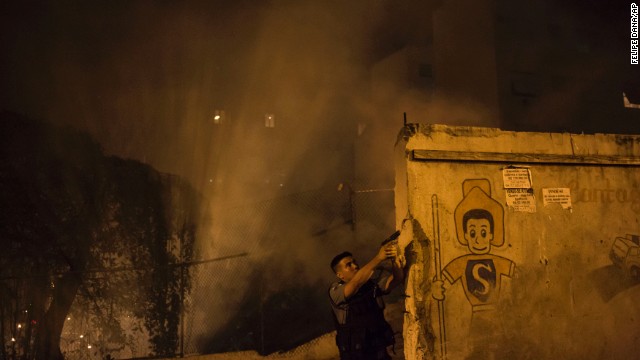 A police officer patrols the area among the smoke from burning barricades.