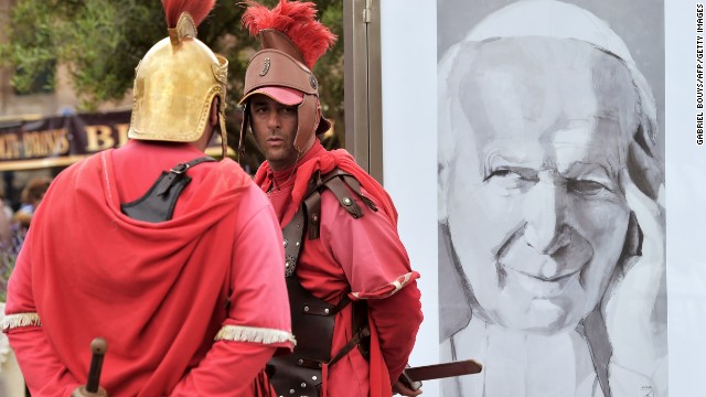 Men dressed as centurions stand by a portrait of Pope John Paul II in Rome during the canonization Mass on April 27.