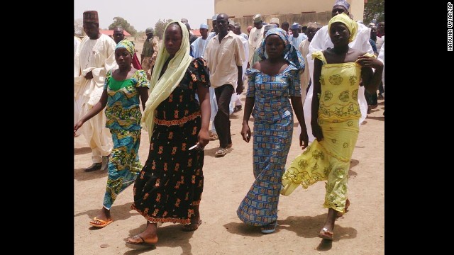 Four female students who were abducted by gunmen and reunited with their families walk in Chibok on Monday, April 21.