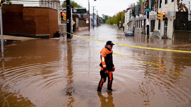 Police officer Robert Jonah walks through floodwaters in the Manayunk neighborhood of Philadelphia on Thursday, May 1. A powerful storm system, including a series of tornadoes, has claimed at least three dozen lives in several states this week.