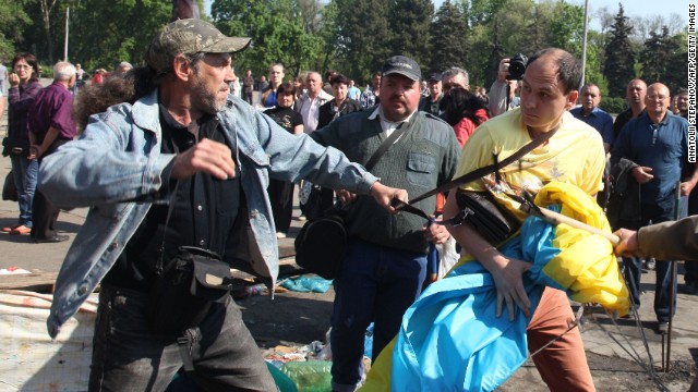 Pro-Russian activists beat a pro-Ukraine supporter trying to save the Ukrainian flag that was removed from a flagpole outside the burned trade union building in Odessa.