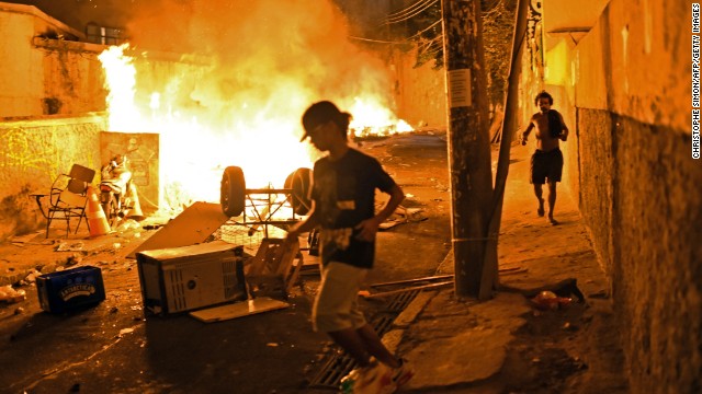 Residents run for cover during violent clashes between protesters and Brazilian Police Special Forces in a favela near Copacabana in Rio on April 22, 2014. Violent protests broke out in the city's landmark beachfront district following the death of a resident during clashes with the army in a nearby favela. 