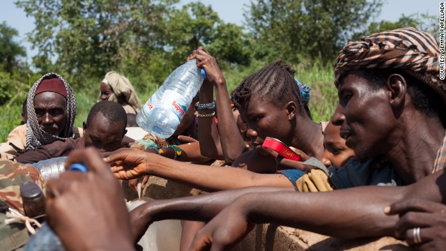 Despite security risks, refugees break away from the group to collect water from a nearby well, after the convoy ran out on the third day of the journey.