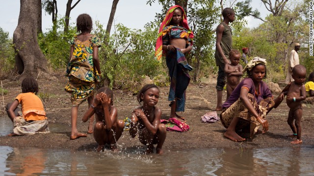 As more mechanical problems with vehicles are addressed on April 30, the fourth day of travel, people wash themselves in a nearby water dam.