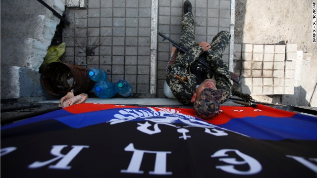 An armed pro-Russian man sits below a flag of the self-proclaimed Donetsk People's Republic at the barricades on a road leading into Slovyansk on May 11. 