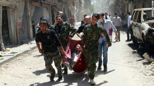 Rescuers carry a man wounded by a mine in the Bustan al-Diwan neighborhood of Homs on May 10.