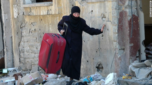 A Syrian woman carries a suitcase along a street in the Juret al-Shayah district of Homs on May 10.