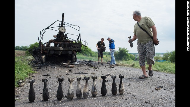 People collect mortar shells in front of a burnt-out Ukrainian military vehicle near Oktyabrskoe, Ukraine, on May 14.