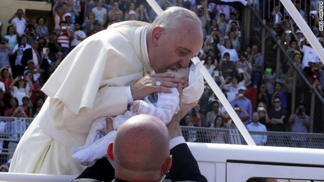 Pope Francis kisses a baby after giving a blessing upon his arrival to lead Mass at the Amman stadium. 