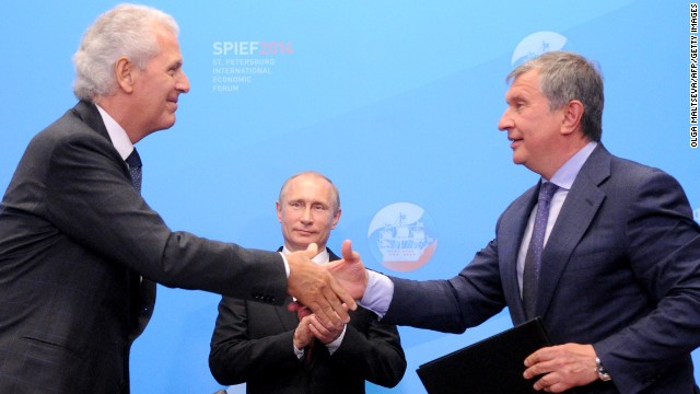 Putin behind Igor Sechin (R), the CEO of Rosneft, and Marco Tronchetti Provera of Italian tire manufacturer Pirelli. 