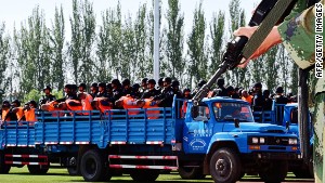 Terror suspects, in orange jumpsuits, held by security forces.