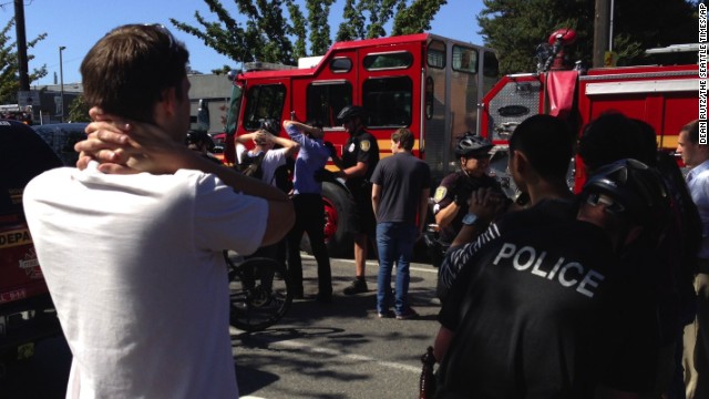 Bystanders look on as emergency personnel arrive near the scene of the shooting.