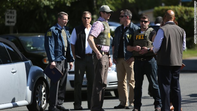 Law enforcement officers gather near the scene. 