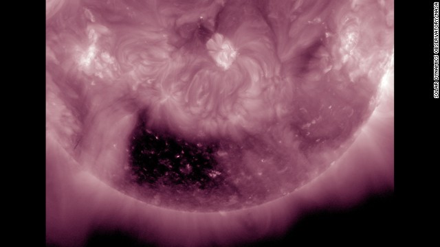 A coronal hole, almost square in its shape, is one of the most noticeable features on the sun on May 5-7, 2014. A coronal hole is an area where high-speed solar wind streams into space. It appears dark in extreme ultraviolet light as there is less material to emit in these wavelengths. Inside the coronal hole you can see bright loops where the hot plasma outlines little pieces of the solar magnetic field sticking above the surface. Because it is positioned so far south on the sun, there is less chance that the solar wind stream will impact us here on Earth. 