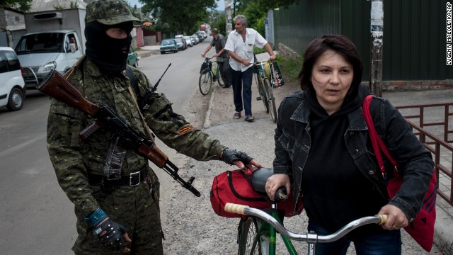 A pro-Russian fighter in Slovyansk, Ukraine, checks a woman's documents as she leaves the city on Thursday, June 12.