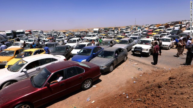 Iraqis fleeing the violence wait in their vehicles at a Kurdish checkpoint in Aski Kalak on June 10.